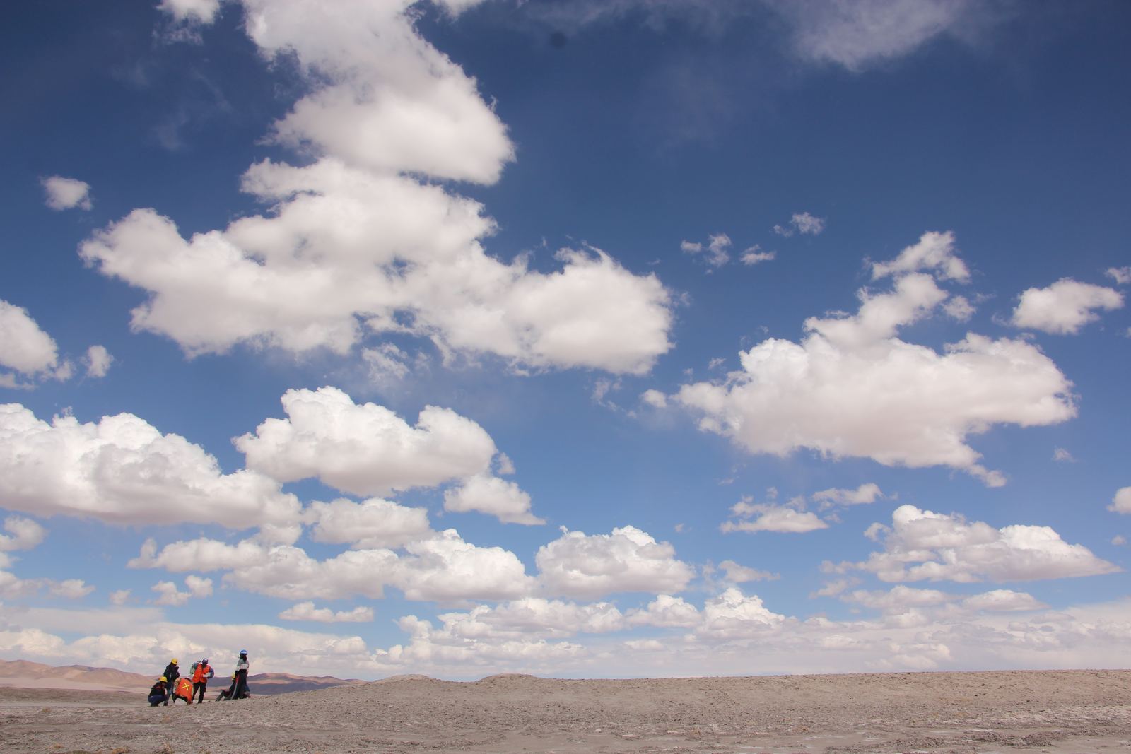 Equipo de campo trabajando en un salar bajo un cielo con nubes